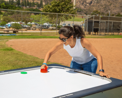 Woman Playing Air Hockey as Company Picnic Entertainment at inVia's Company Cookout in Malibu, CA